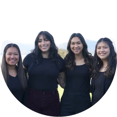 Four woman employees holding each others and smiling outside.